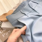 Hellblaue Stoffhose mit elastischem Bund und Knopfdetail, ideal für Sommermode. Hochwertiger, leichter Stoff für maximalen Tragekomfort.