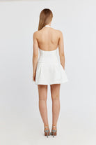 Weißes, rückenfreies Minikleid mit Neckholder-Design, ideal für Sommermode. Perfekt kombiniert mit eleganten High Heels für stilvolle Anlässe.