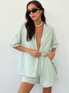 Frau in gestreiftem, mintgrünem Sommeranzug, trägt Sonnenbrille und Perlenkette. Modetrend, Damenmode, lässiger Stil, Sommeroutfit.
