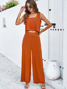 Frau in orangefarbenem Sommeroutfit vor weißer Wand, modisch mit Sonnenbrille. Perfekt für Strandmode, lässiger Look, Damenbekleidung.