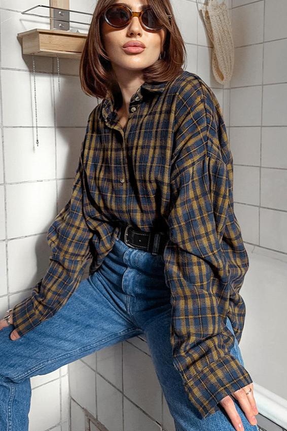 Frau in kariertem Hemd und blauer Jeans, trägt Sonnenbrille. Modetrend, lässiger Stil, Herbstmode, Damenbekleidung, urbaner Look.