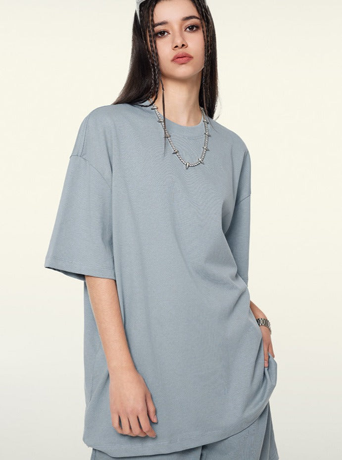 Frau in lockerem, hellblauem Oversize-T-Shirt, modisch mit Kette. Trendige Damenmode, lässiger Stil, Streetwear, bequemes Outfit.