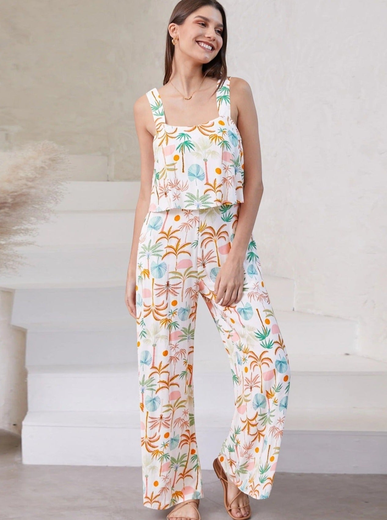 Frau in geblümtem Sommeranzug, ärmelloses Top und weite Hose, lächelnd, modisch, bequem, ideal für warme Tage, trendige Damenmode.