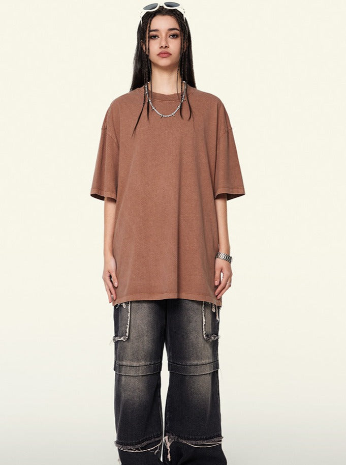 Braunes Oversize-T-Shirt, kombiniert mit weiten, dunklen Jeans und Ketten-Accessoires. Trendige Streetwear für Damen, lässiger Look.