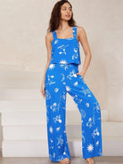 Frau in blauem Jumpsuit mit weißem, maritimem Muster. Sommermode, Damenbekleidung, lässiger Stil, Strandoutfit, modisch, bequem.