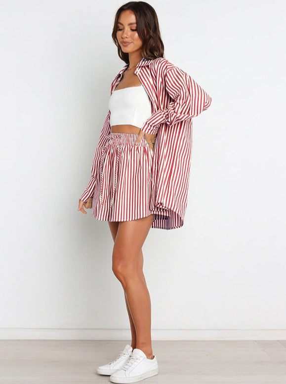 Gestreiftes Damen-Outfit: Rot-weißes Hemd und Rock-Set, kombiniert mit weißem Crop-Top und Sneakers. Modetrend, lässiger Sommerlook.