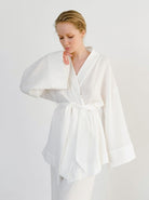 Frau in weißem Kimono-Bademantel aus Baumwolle, minimalistisch und elegant. Perfekt für Spa, Wellness und Entspannung zu Hause.
