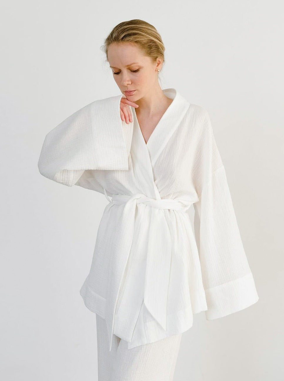 Frau in weißem Kimono-Bademantel aus Baumwolle, minimalistisch und elegant. Perfekt für Spa, Wellness und Entspannung zu Hause.