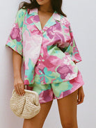 Farbintensives Damen-Set mit Blumenmuster, bestehend aus Hemd und Shorts, ideal für Sommermode. Perfekt kombiniert mit einer geflochtenen Tasche.