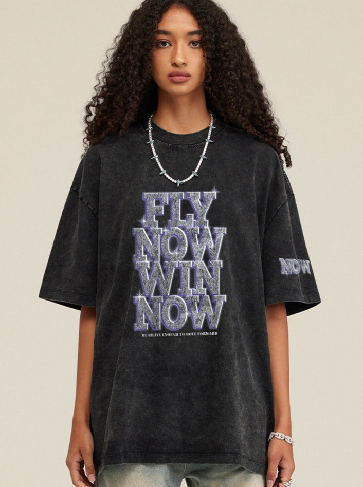 Schwarzes Oversize-T-Shirt mit "Fly Now Win Now"-Aufdruck, lässiger Streetwear-Stil, ideal für trendige Mode und urbanen Look.