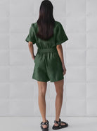 Frau in grünem Jumpsuit, Rückansicht, modisch, Sommeroutfit, Damenmode, bequeme Kleidung, stilvoll, Freizeitlook, trendige Sandalen.