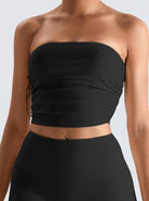 Schwarzes trägerloses Crop-Top aus geripptem Stoff, ideal für Sommermode, kombiniert mit passendem Rock. Perfekt für stilvolle Freizeitlooks.