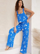 Frau in blauem Jumpsuit mit weißem, maritimem Muster. Sommermode, lässiger Stil, ideal für Strand und Freizeit. Trendige Damenbekleidung.