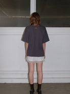 Frau in schwarzem T-Shirt und weißer Spitzenhose, steht vor einem Fenster. Modetrend, lässiger Stil, urbaner Look, Streetwear.