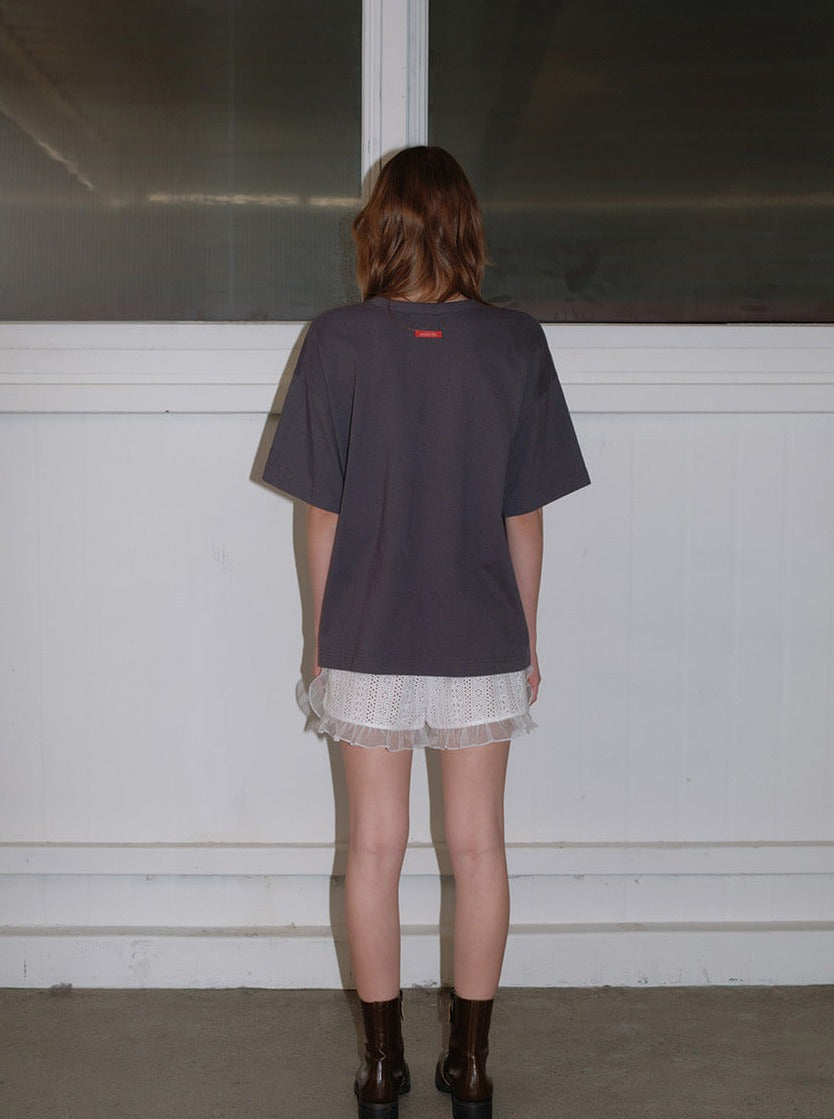 Frau in schwarzem T-Shirt und weißer Spitzenhose, steht vor einem Fenster. Modetrend, lässiger Stil, urbaner Look, Streetwear.