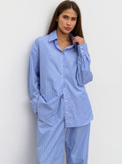 Frau in gestreiftem, blau-weißem Pyjama-Set aus Baumwolle, lässig und bequem, ideal für entspannte Nächte. Perfekte Nachtwäsche für Damen.