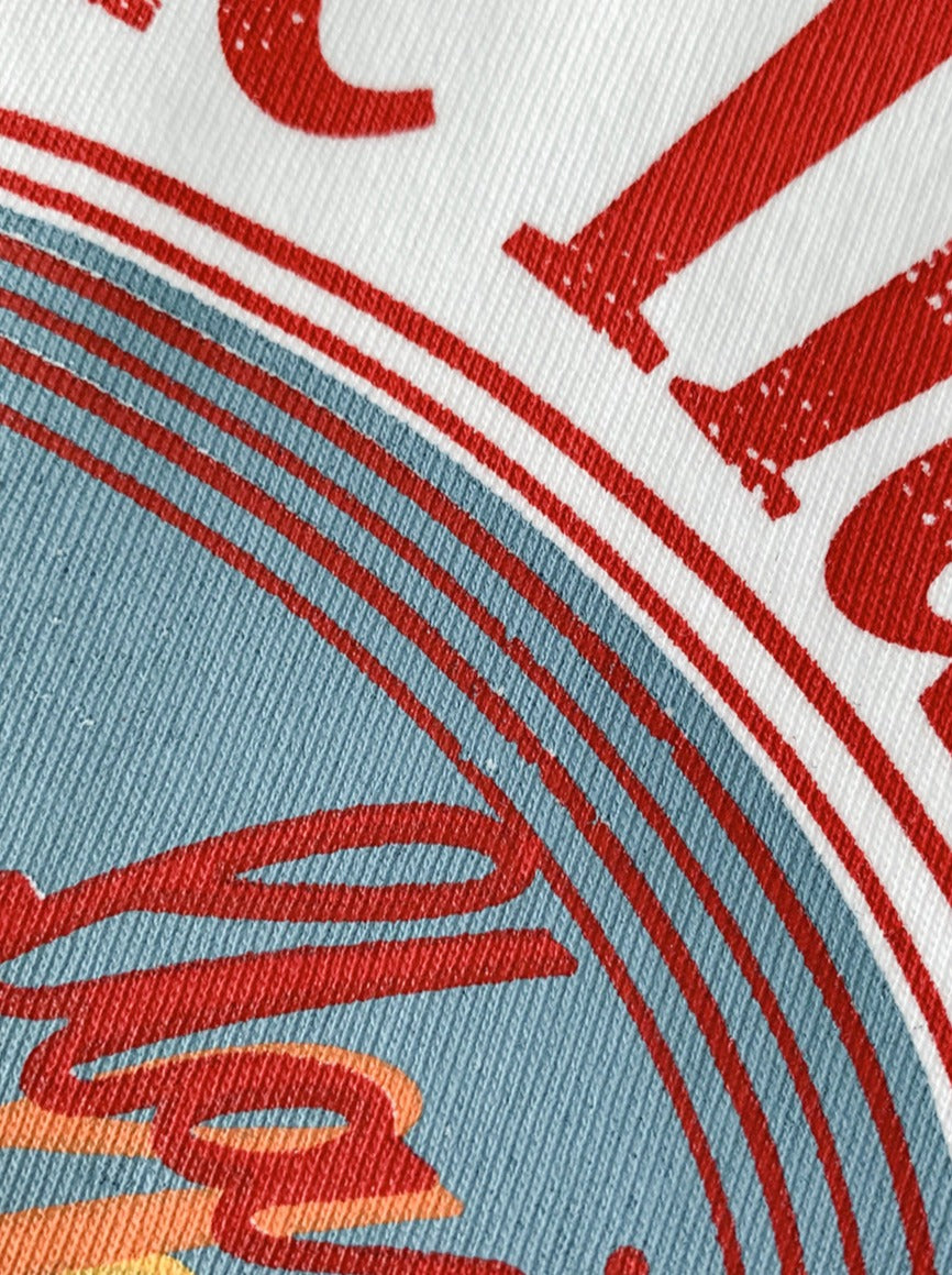 Nahaufnahme eines Vintage-Logos auf Stoff, mit roten und blauen Grafiken. Ideal für Retro-Designs, Textildruck, Mode und Grafikdesign.