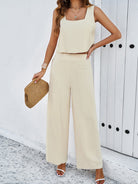 Damen Sommer Outfit: Elegantes, ärmelloses Top und weite Hose in Beige, ideal für Strandmode. Perfekt kombiniert mit Strohtasche und Sandalen.