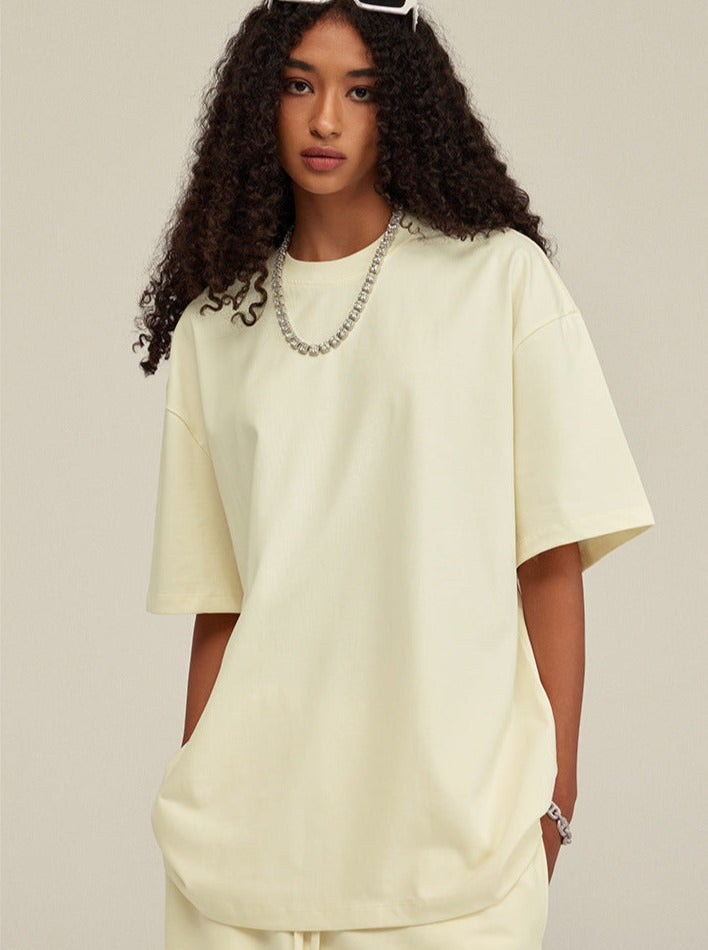 Frau in cremefarbenem Oversize-T-Shirt, modisch, lässig, mit Kette. Perfekt für Streetwear, Trendmode, bequemes Outfit, urbaner Stil.