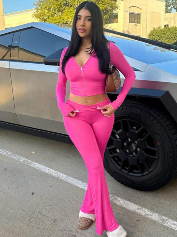 Frau in pinkem Trainingsanzug vor futuristischem Auto. Modetrend, Streetstyle, sportlich-elegant, urbaner Look, stilvolle Freizeitkleidung.