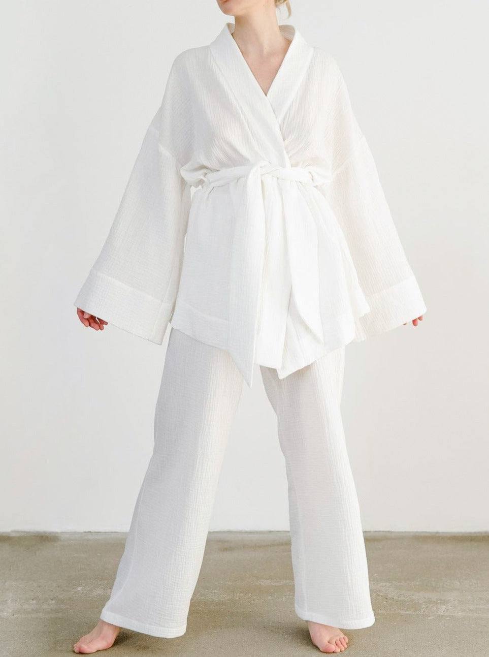 Frau in weißem Kimono-Set aus Baumwolle, ideal für Yoga oder Lounge. Bequeme, weite Passform, modisch und atmungsaktiv. Perfekt für Zuhause.