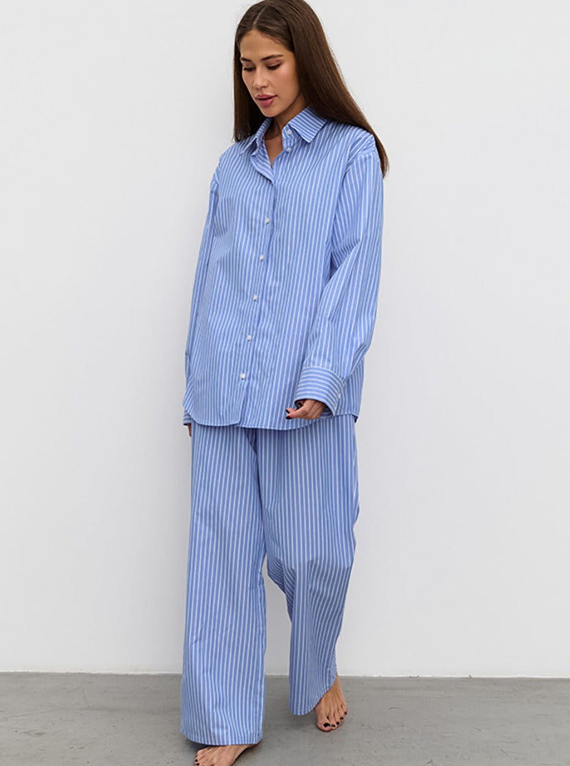 Frau in gestreiftem blauen Pyjama-Set, bestehend aus lockerem Hemd und weiten Hosen. Bequem, modisch, ideal für entspannte Nächte.