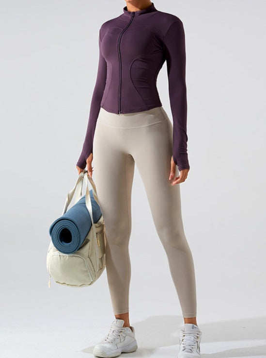 Damen-Sportbekleidung: Lila Jacke, beige Leggings, weiße Sneaker. Fitness-Outfit mit Yogamatte und Tasche. Ideal für Yoga und Workout.