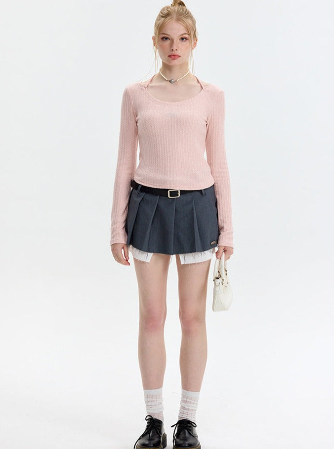 Damenmode: Eleganter Look mit rosa Pullover, grauem Faltenrock und schwarzem Schuhwerk. Perfekt für trendige Herbst-Outfits und Streetstyle.