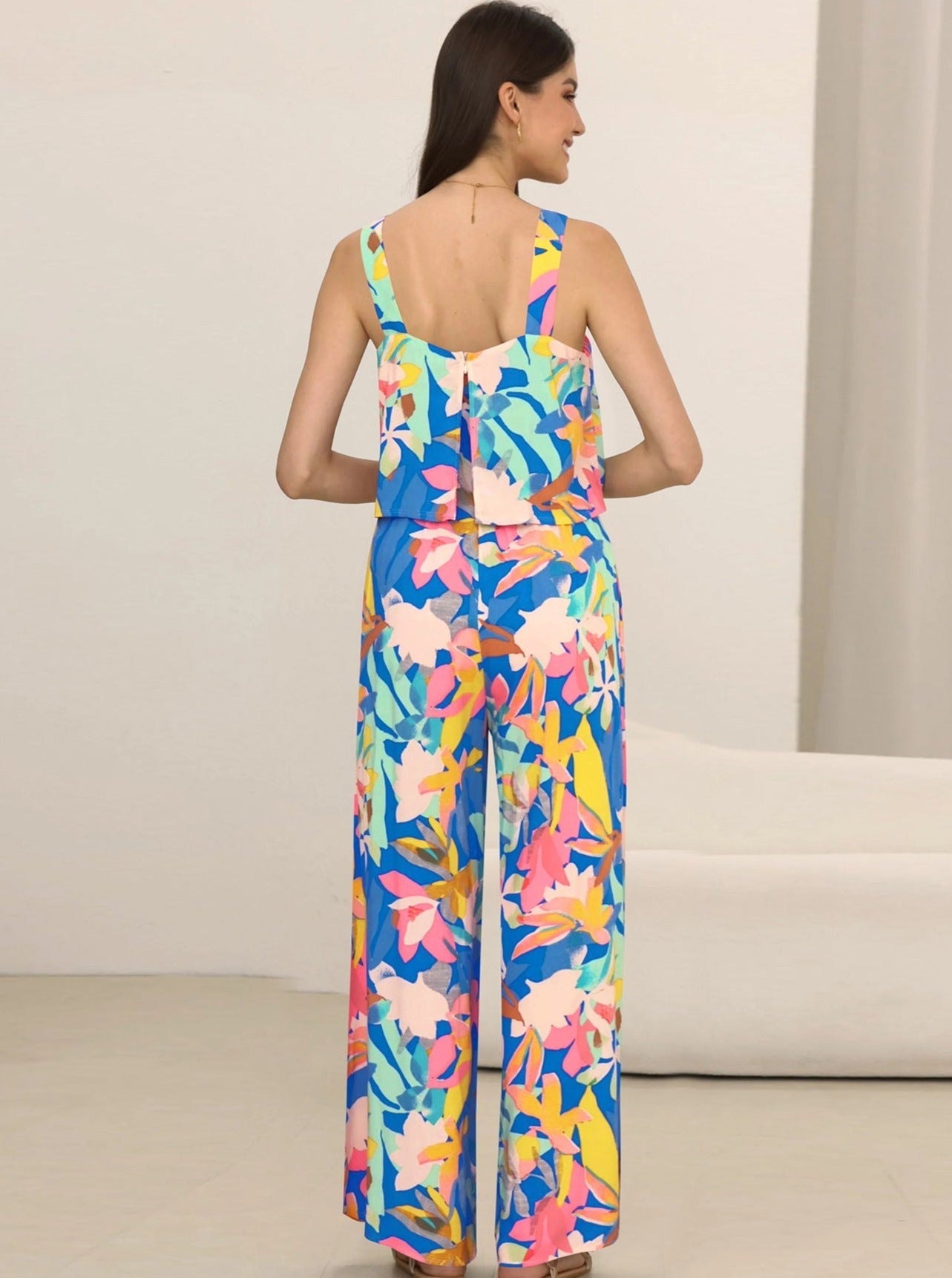 Frau in buntem, floralen Jumpsuit aus leichter Baumwolle, ideal für Sommermode. Perfekt für Strand, Urlaub und Freizeit.