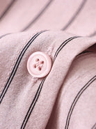 Rosa Hemdknopf auf gestreiftem Stoff, Nahaufnahme. Hochwertige Baumwolle, elegante Streifen, modisches Design, ideal für stilvolle Outfits.