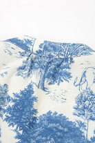 Blau-weißes Toile-de-Jouy-Muster auf Stoff, zeigt detaillierte Landschaftsszenen mit Bäumen und Tieren. Ideal für Vintage-Mode und Heimtextilien.