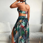 Frau in tropischem Bikini-Set mit floralem Muster, bestehend aus Bandeau-Top und Maxirock, posiert auf weißem Sofa. Sommermode, Strandkleidung.