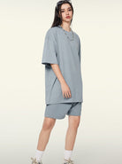 Frau in lockerem, hellblauem Oversize-T-Shirt und Shorts, modisch, lässig, Streetwear, Sommeroutfit, trendige Damenmode, urbaner Stil.