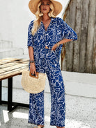 Frau in blau-weißem Sommeranzug mit abstraktem Muster, Strohhut und geflochtener Tasche. Perfekt für Strandmode und Sommeroutfits.