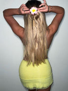 Frau mit langen blonden Haaren, gelbem Spitzenrock und Blumen-Haarspange. Sommermode, Haaraccessoire, trendiger Look.