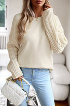 Damenpullover mit Zopfmuster, cremefarben, kombiniert mit hellblauer Jeans. Modetrend, Strickmode, Herbstoutfit, eleganter Look.