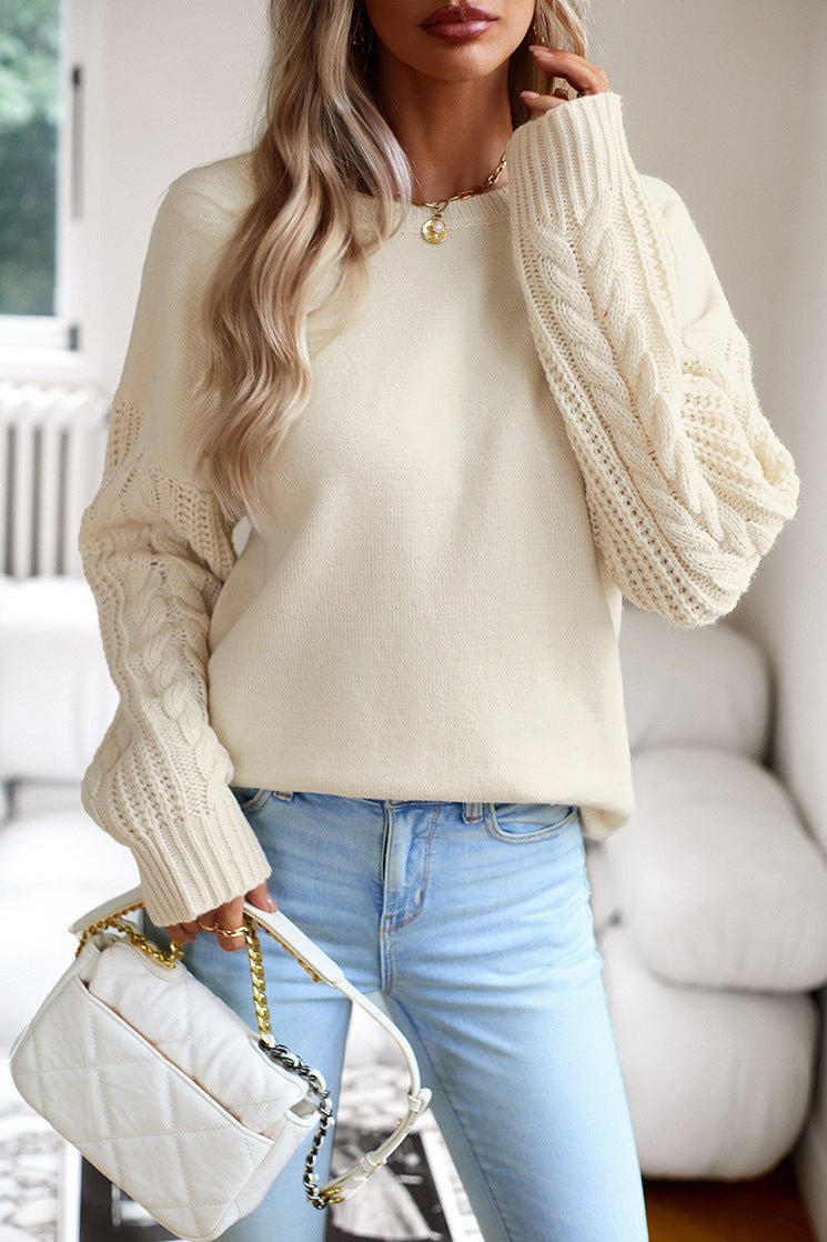 Damenpullover mit Zopfmuster, cremefarben, kombiniert mit hellblauer Jeans. Modetrend, Strickmode, Herbstoutfit, eleganter Look.