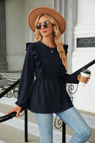 Elegante Frau mit Sonnenbrille und Hut, trägt dunkelblaues Rüschenoberteil und Jeans, hält Kaffeebecher. Modetrends, Damenmode, Streetstyle.