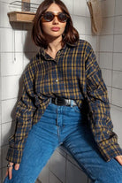 Frau in kariertem Hemd und blauer Jeans, trägt Sonnenbrille. Modetrend, lässiger Stil, urbane Mode, Herbstoutfit, Damenbekleidung.