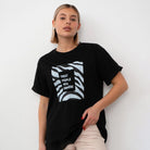 Frau trägt schwarzes T-Shirt mit "Treat People With Kindness"-Aufdruck, modisches Design, lässiger Stil, ideal für trendige Streetwear-Looks.