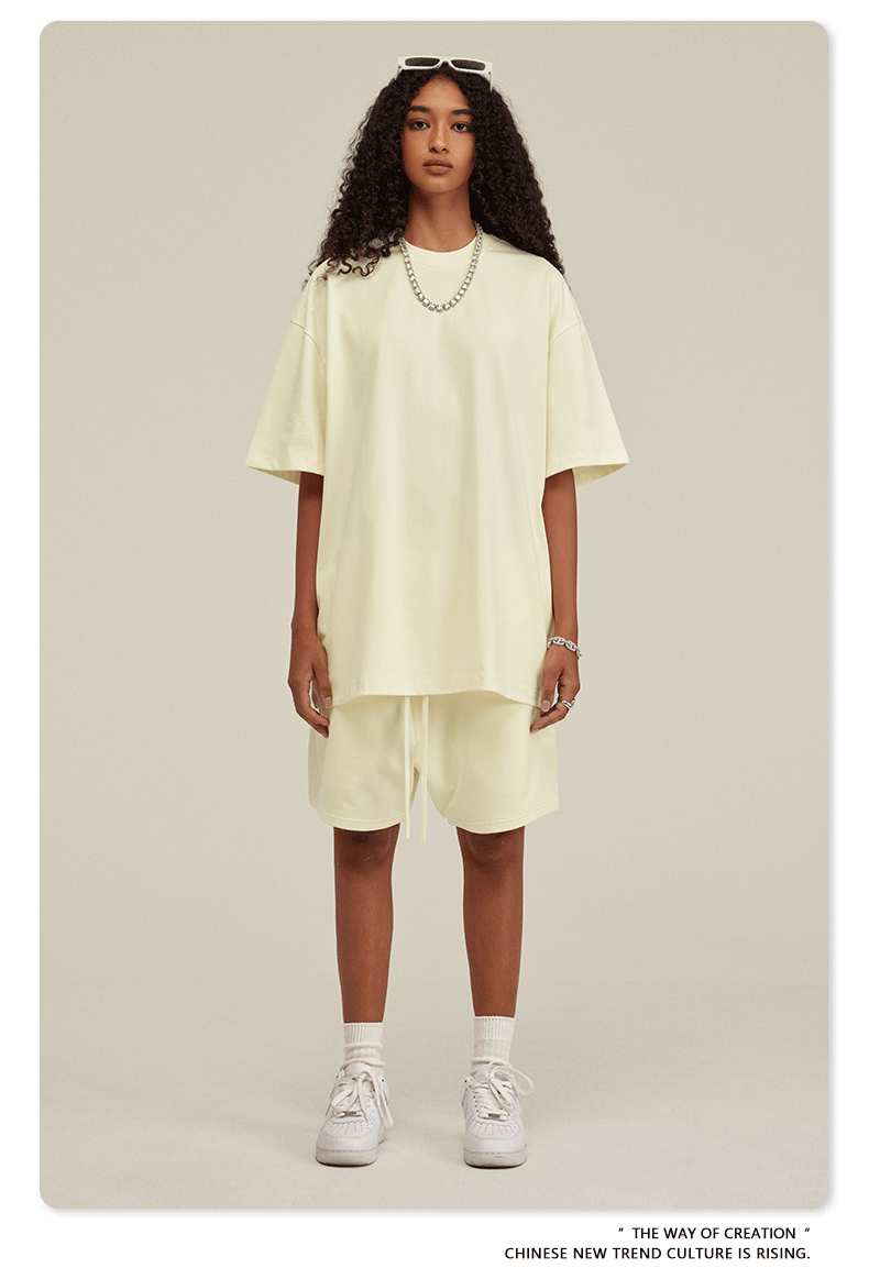 Frau in cremefarbenem Oversize-T-Shirt und Shorts, trägt weiße Sneakers. Modetrend, lässiger Stil, urbaner Look, minimalistische Kleidung.