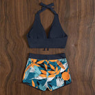 Damen-Bikini-Set mit schwarzem Neckholder-Oberteil und tropisch bedruckten Shorts. Perfekt für Strandmode und Sommerurlaub.