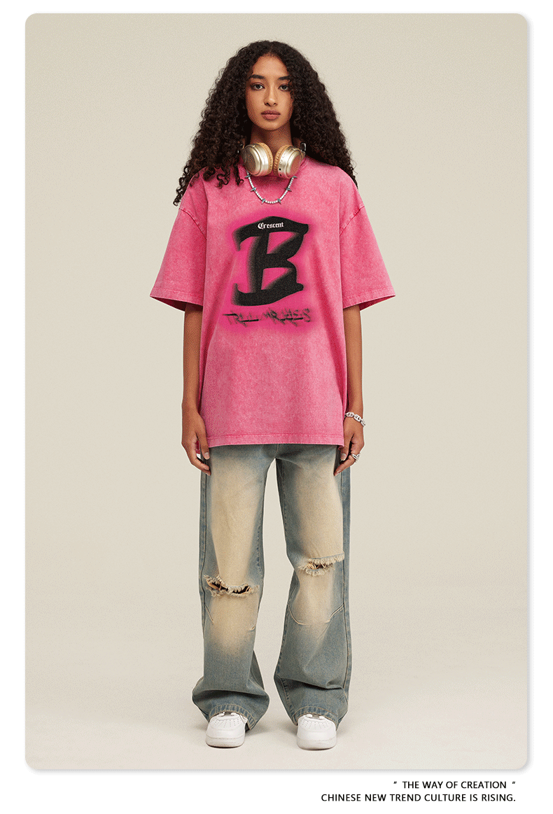 Frau in rosa Oversize-T-Shirt mit schwarzem "B"-Logo, weiten Jeans und Kopfhörern. Modetrend, Streetwear, lässiger Stil, urbaner Look.