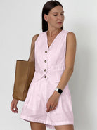 Frau in rosa Leinenanzug mit Knöpfen, brauner Ledertasche und Smartwatch. Sommermode, eleganter Look, Damenbekleidung, Freizeitoutfit.