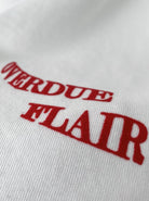 Weißes T-Shirt mit rotem Aufdruck "OVERDUE FLAIR", modisches Design, hochwertige Baumwolle, trendige Streetwear, lässiger Stil.