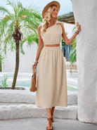 Elegantes, ärmelloses Maxikleid in Beige, ideal für Sommermode. Perfekt für Strandurlaube und Freizeit. Kombiniert mit Strohhut und Sandalen.