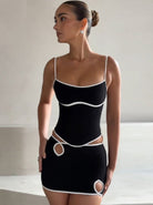 Schwarzes Minikleid mit weißen Akzenten, Spaghettiträgern und Cut-Out-Details. Elegantes Design, ideal für Partys und Abendmode.