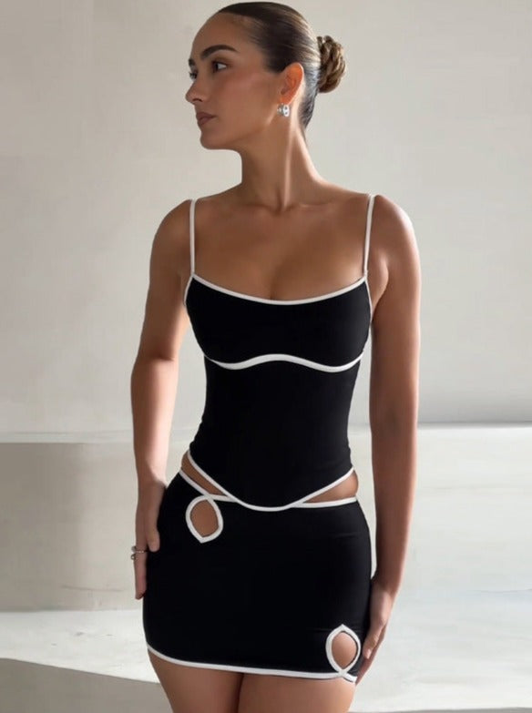 Schwarzes Minikleid mit weißen Akzenten, Spaghettiträgern und Cut-Out-Details. Elegantes Design, ideal für Partys und Abendmode.