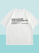 Weißes T-Shirt mit schwarzem Aufdruck "DREAMAGE THE MIDNIGHTS". Modisches Unisex-Shirt, ideal für Streetwear und Casual-Looks.