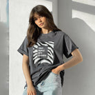 Frau in grauem T-Shirt mit "Treat People With Kindness"-Aufdruck, lässiger Look, modische Damenbekleidung, trendige Streetwear, Jeans.